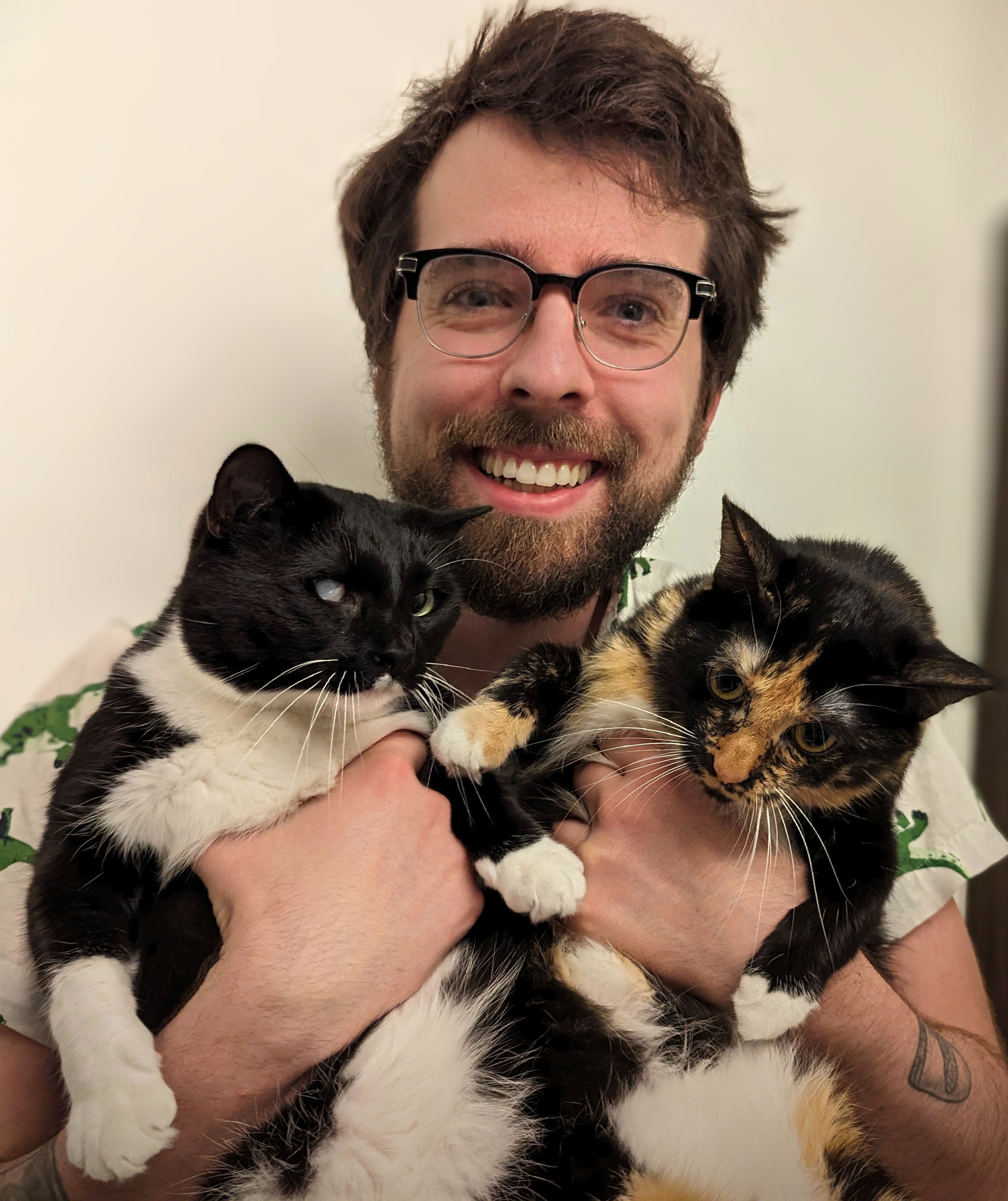 Picture of Alex Bates holding two cats