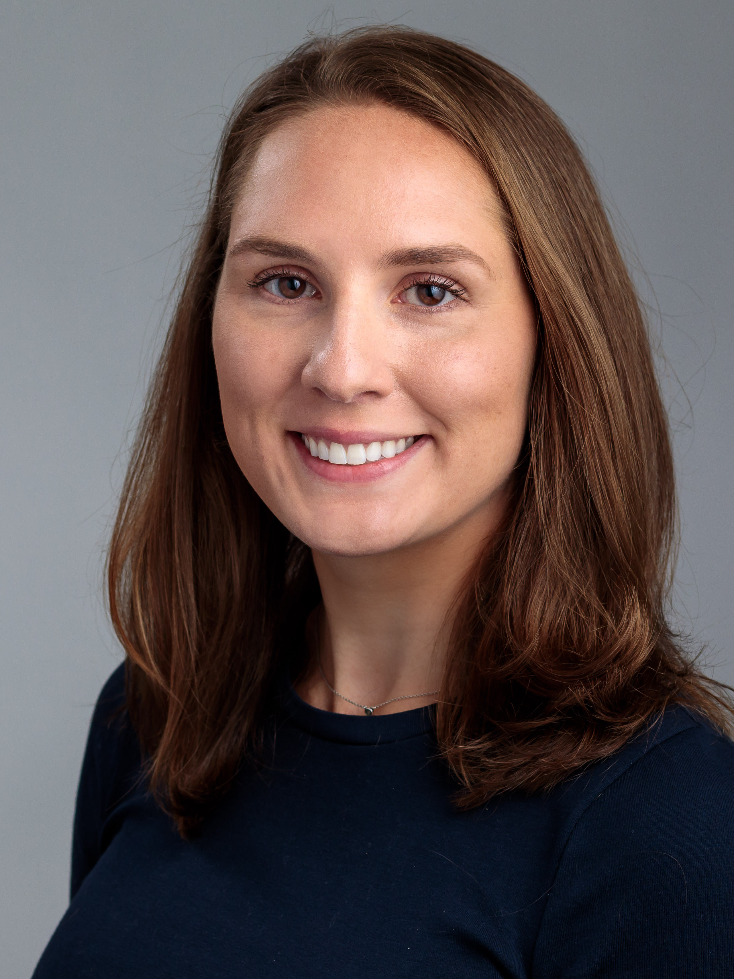 Formal headshot of Laura Stoff in a black top in front of a grey background