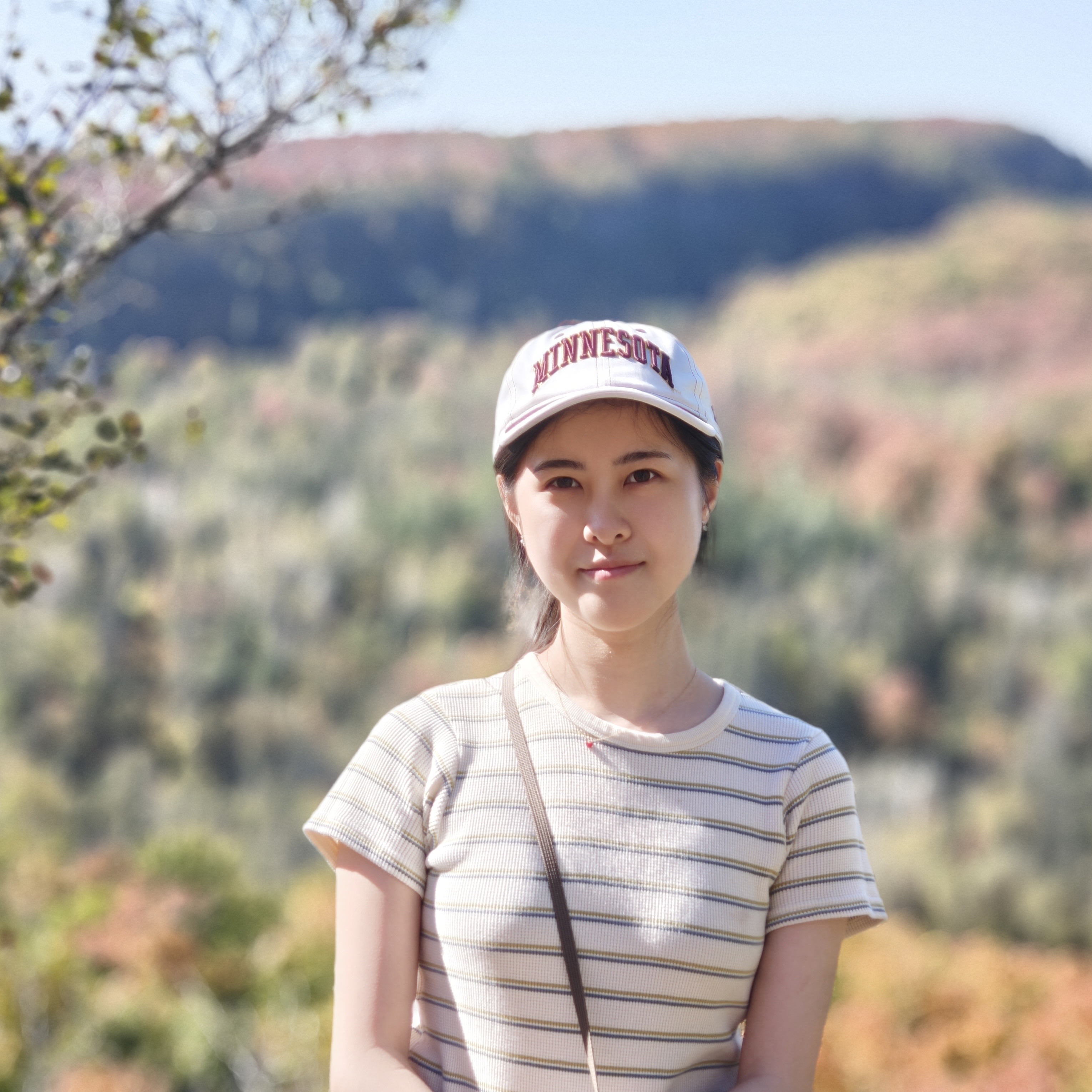 Picture of Yike Tang in a light colored shirt with stripes in a scenic area